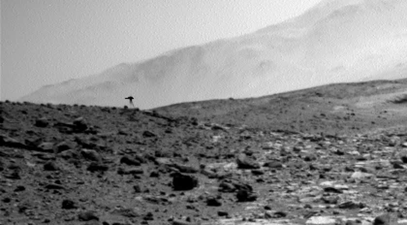 キュリオシティが撮影した火星画像の左下部分を拡大したもの。地平線付近に、傘と二本脚のような形を伴う小さな黒い像が見える。